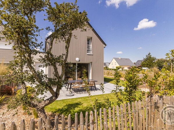 A modern two-story house with a patio area featuring outdoor furniture. - Contemporary House in Portbail - Private Garden and Internet Included (Portbail)