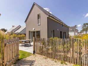 A modern two-story house with a sloped roof, a wooden fence, and a gravel driveway. - Contemporary House in Portbail - Private Garden and Internet Included (Portbail)