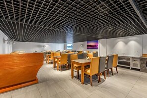 A modern restaurant with a grid-patterned ceiling, wooden reception desk, and multiple dining tables with chairs. - Vienna Classic Hotel (Hangzhou)