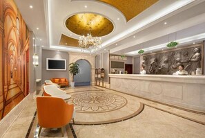 A hotel lobby with a reception desk, seating area, and a decorative ceiling. - Vienna Classic Hotel (Hangzhou)