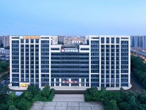 A multi-story building with a central entrance and a sign above it. - Vienna Classic Hotel (Hangzhou)