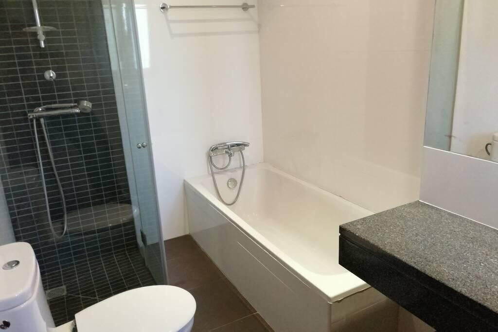Ein Badezimmer mit Badewanne, Toilette und einer Duschkabine aus Glas.