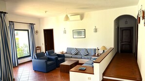 A living room with a sofa, chairs, a coffee table, and a staircase leading to a door. - Casa Azevedo - Vilamoura (Vilamoura)