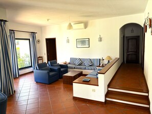A living room with a sofa, chairs, a coffee table, and a staircase leading to a door.