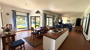 A spacious living area with a dining table, chairs, a sofa, and a television. - Casa Azevedo - Vilamoura (Vilamoura)