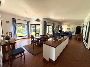 A spacious living area with a dining table, chairs, a sofa, and a television.