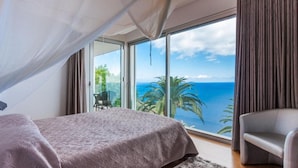 Une chambre avec un lit, une chaise et une vue sur l’océan.