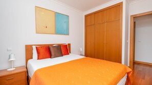 Una camera d'albergo con un letto, un comodino, una lampada, un armadio e un quadro appeso al muro.