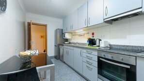 A compact kitchen with a microwave, toaster, and coffee maker on the countertop, a sink, and a stove. - Aidan Apartment by LovelyStay (Funchal)