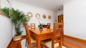 Un coin repas avec une table et des chaises en bois, entouré de plantes en pot et agrémenté de miroirs décoratifs fixés au mur.