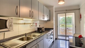 A modern kitchen with stainless steel appliances, a granite countertop, and a sliding glass door leading to an outdoor patio. - Aidan Apartment by LovelyStay (Funchal)