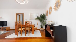 Un soggiorno moderno con zona pranzo, televisore a schermo piatto, mobili in legno, una pianta in vaso e decorazioni a parete.