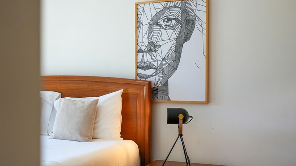 A bedroom with a wooden headboard, white bedding, and a wall-mounted artwork. - Aidan Apartment by LovelyStay (Funchal)