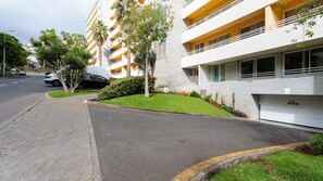 Un edificio residenziale a più piani con balconi, un vialetto lastricato e un'area parcheggio.