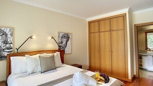 A bedroom with a bed, bedside lamps, a wardrobe, and a breakfast tray with croissants and grapes. - Aidan Apartment by LovelyStay (Funchal)