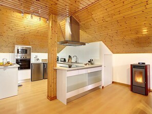 Una cucina moderna con soffitto in legno, elettrodomestici integrati e un'isola centrale.