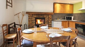 A cozy dining area with a brick fireplace, wooden chairs, and a round table set for four.