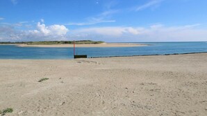 A beach with a sandy shore, a clear blue sky, and a distant dune. - Independent house in Portbail, pets allowed, near the beach (Portbail)