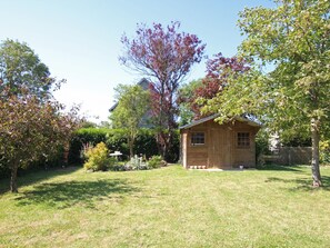 A wooden cabin with a small porch, surrounded by a well-maintained lawn and various trees. - Village house with private garden, perfect for families (Orval sur Sienne)