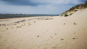 A beach with sand dunes and a cloudy sky.