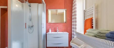 A bathroom with a glass-enclosed shower, a white sink, and a mirror above it.
