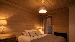 Ein Schlafzimmer mit Holzwandverkleidung, einem Bett, einem Nachttisch und einer Pendelleuchte.