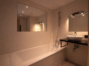 A modern bathroom with a bathtub, a large mirror, and a sink. - Stunning duplex in Courchevel - 3 bedrooms, parking, WiFi (Courchevel)