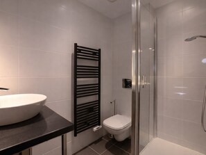 A modern bathroom with a white sink, a black towel rack, a toilet, and a glass-enclosed shower area. - Stunning duplex in Courchevel - 3 bedrooms, parking, WiFi (Courchevel)
