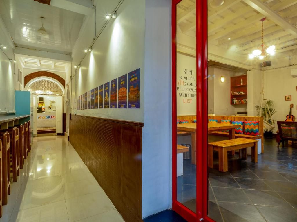 A hotel lobby with a long corridor, a reception desk, and a seating area with tables and chairs.
