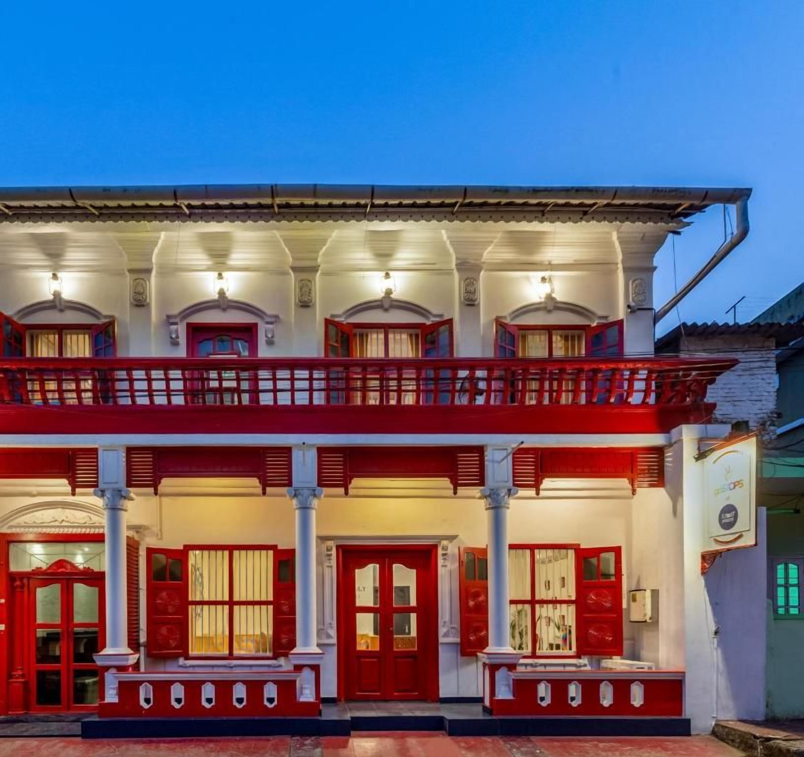 A two-story building with a balcony and a red door.