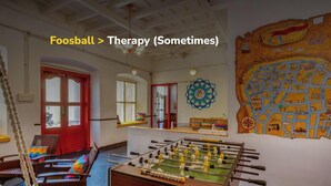 Una habitación con una mesa de futbolín, un mapa grande en la pared y una puerta roja.