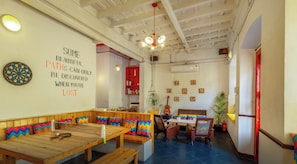 Un espacio de trabajo acogedor con una mesa de madera, bancos y un dardo. Hay una frase motivacional en la pared y un cartel que indica Wi-Fi gratuito.