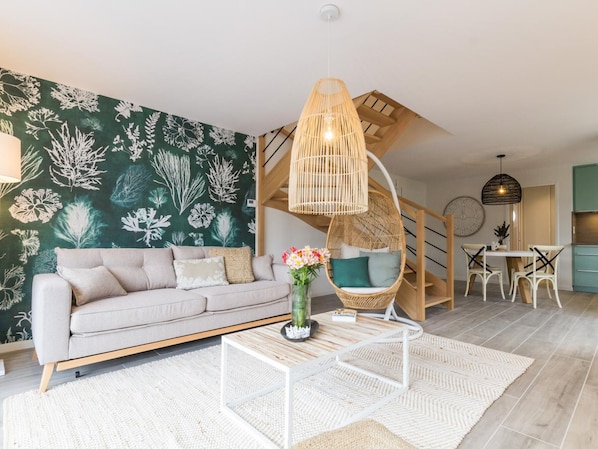 A modern living room with a sofa, coffee table, and a hanging chair.