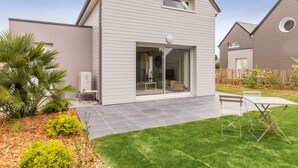 Ein modernes, zweistöckiges Haus mit einem großen Glastür-Eingang, einem kleinen Balkon und einem gepflegten Rasen.
