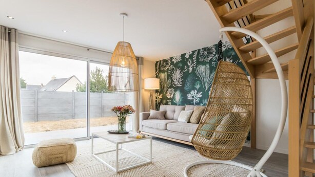 Ein modernes Wohnzimmer mit Sofa, Couchtisch, Hängekorbschaukel und einer Treppe.
