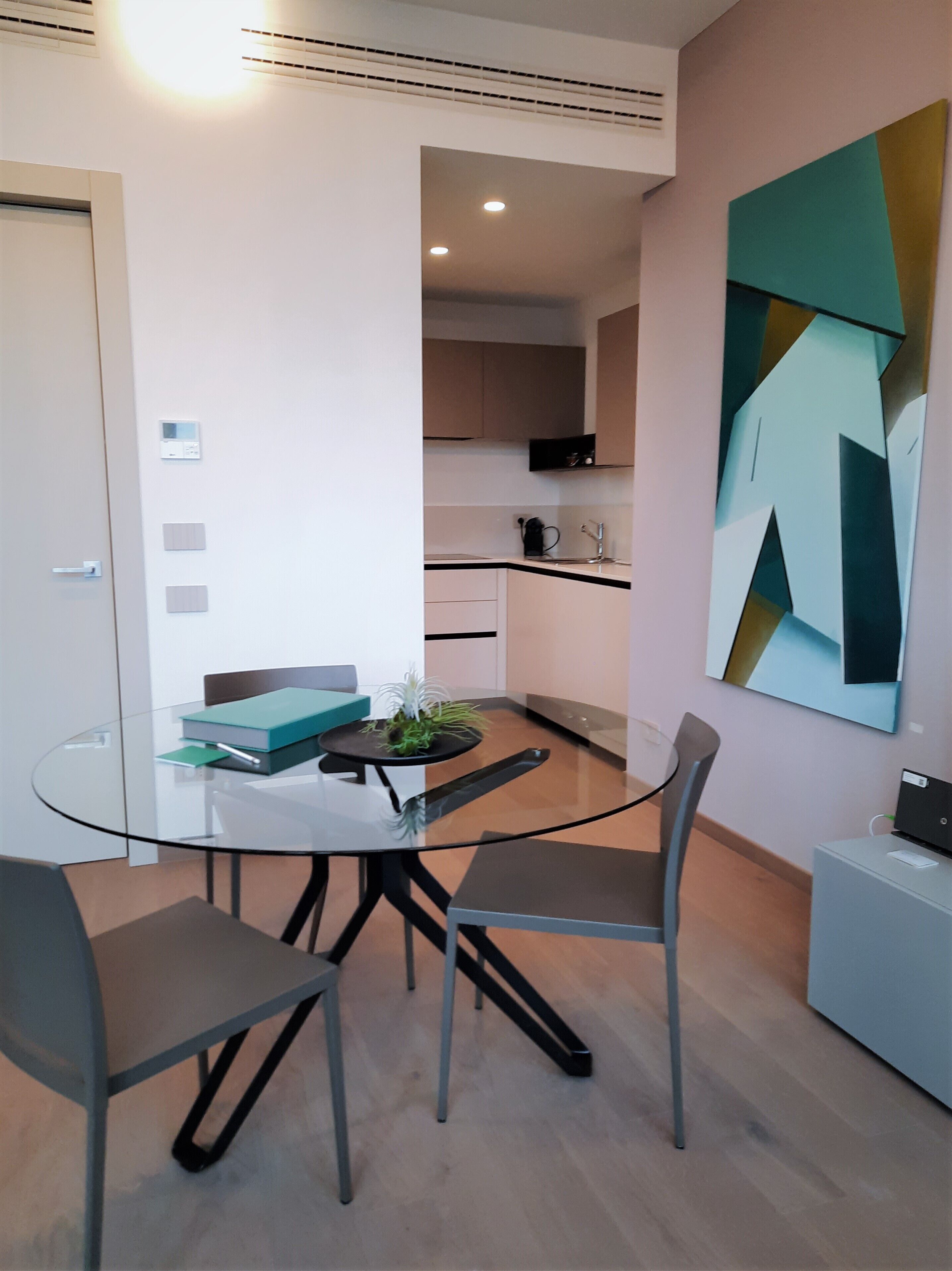 A modern dining area with a glass table, metal chairs, and a small potted plant.
