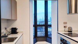 Una cocina moderna con un ventanal grande, electrodomésticos de acero inoxidable y vistas a la ciudad.