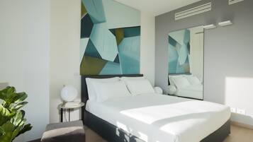 A modern bedroom with a large bed, a bedside table, a mirror, and abstract wall art.