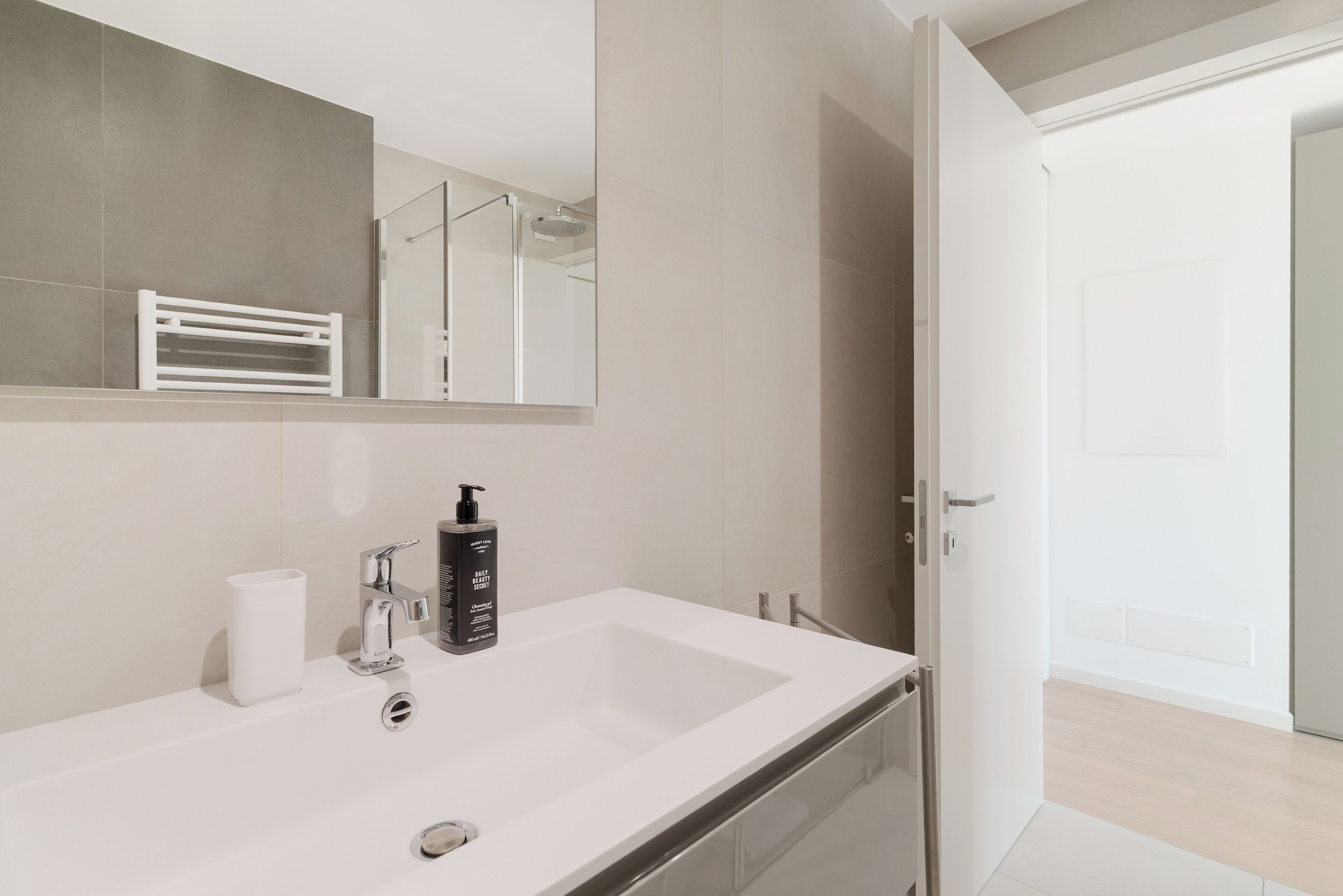 Un baño moderno con un espejo grande, un lavabo blanco y una zona de ducha.