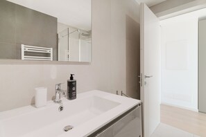 Un baño moderno con un espejo grande, un lavabo blanco y una zona de ducha.