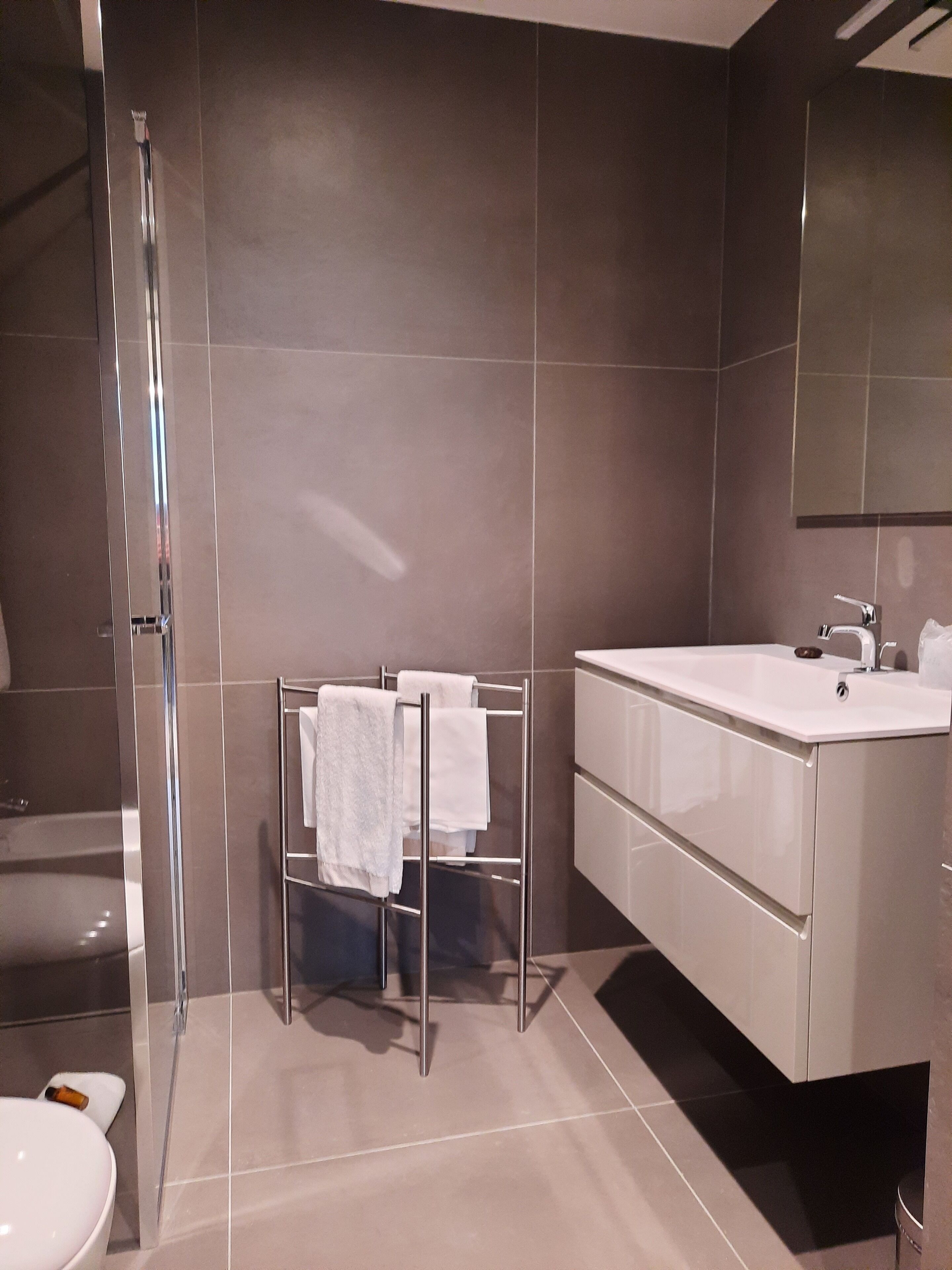 A modern bathroom with a glass shower enclosure, a white sink, and a large mirror.
