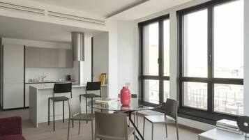 Un apartamento moderno con cocina, comedor y amplios ventanales que ofrecen vistas de la ciudad.