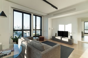 Una sala de estar moderna con un gran ventanal, un sofá, un televisor y una pequeña mesa.