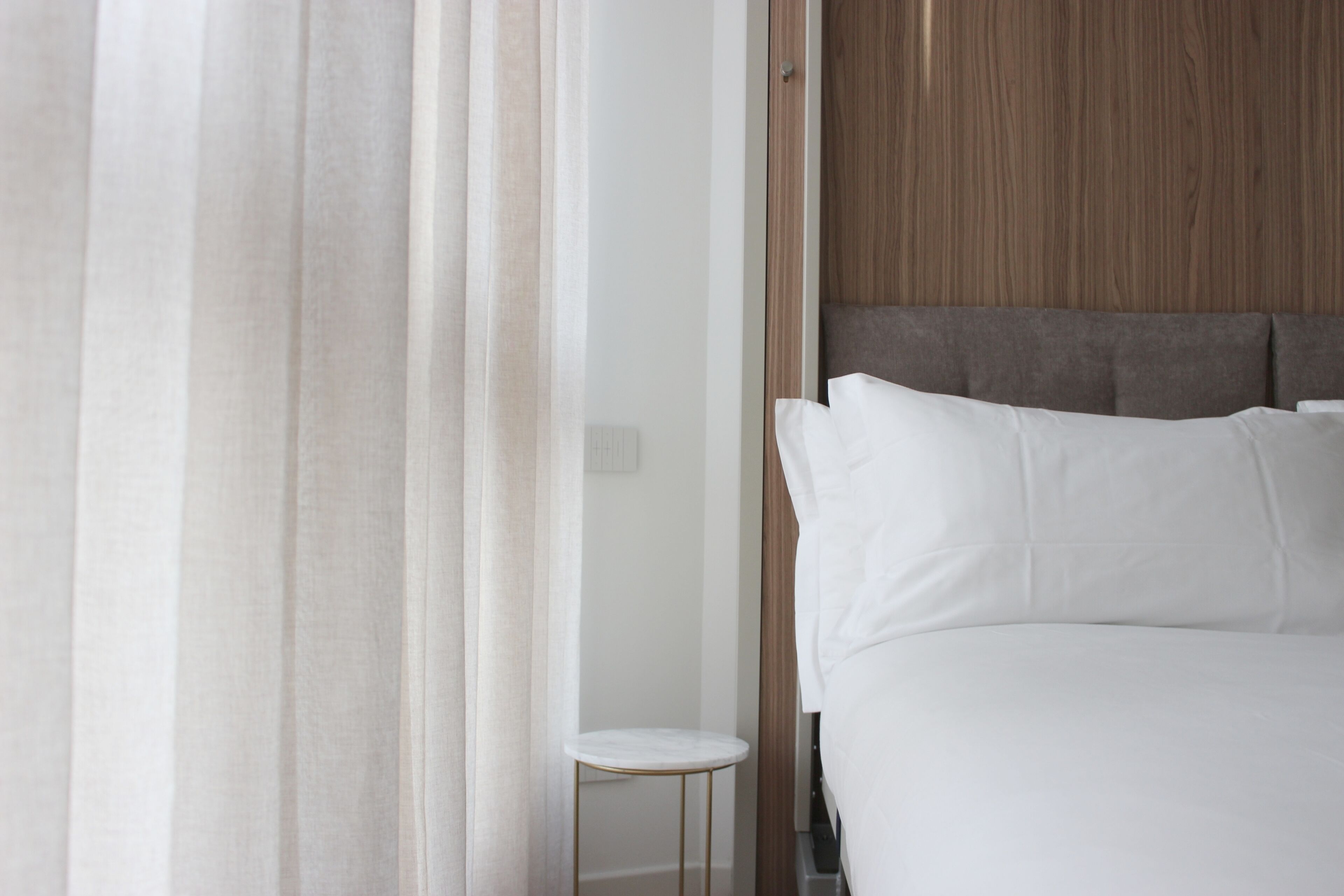 A hotel room with a bed, a small round table, and a wooden headboard.