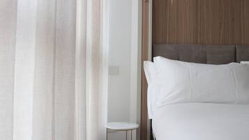 Habitación de hotel con cama, una mesita redonda y cabecero de madera.