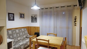 Ett mysigt vardagsrum med en soffa i trä, ett matbord med stolar och en taklampa.