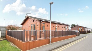 A single-story wooden building with a fenced yard, a street lamp, and a clear sky. - 2 Bed Cabin - Sleeps 4 - Pets - 5 min to Beach (Bridlington)