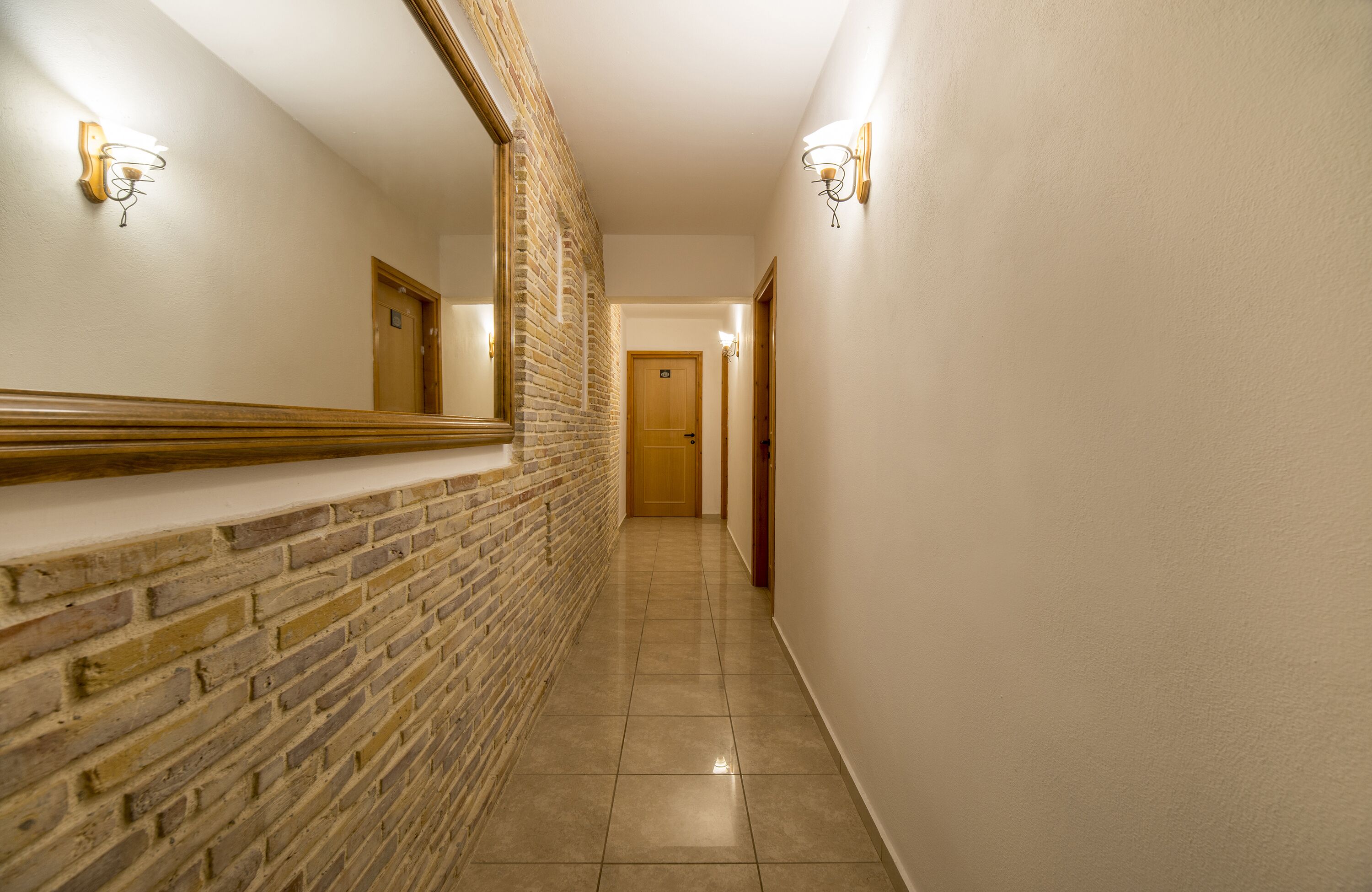 A hallway with a brick wall and a wooden door at the end.