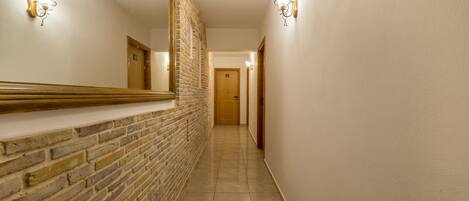 A hallway with a brick wall and a wooden door at the end.