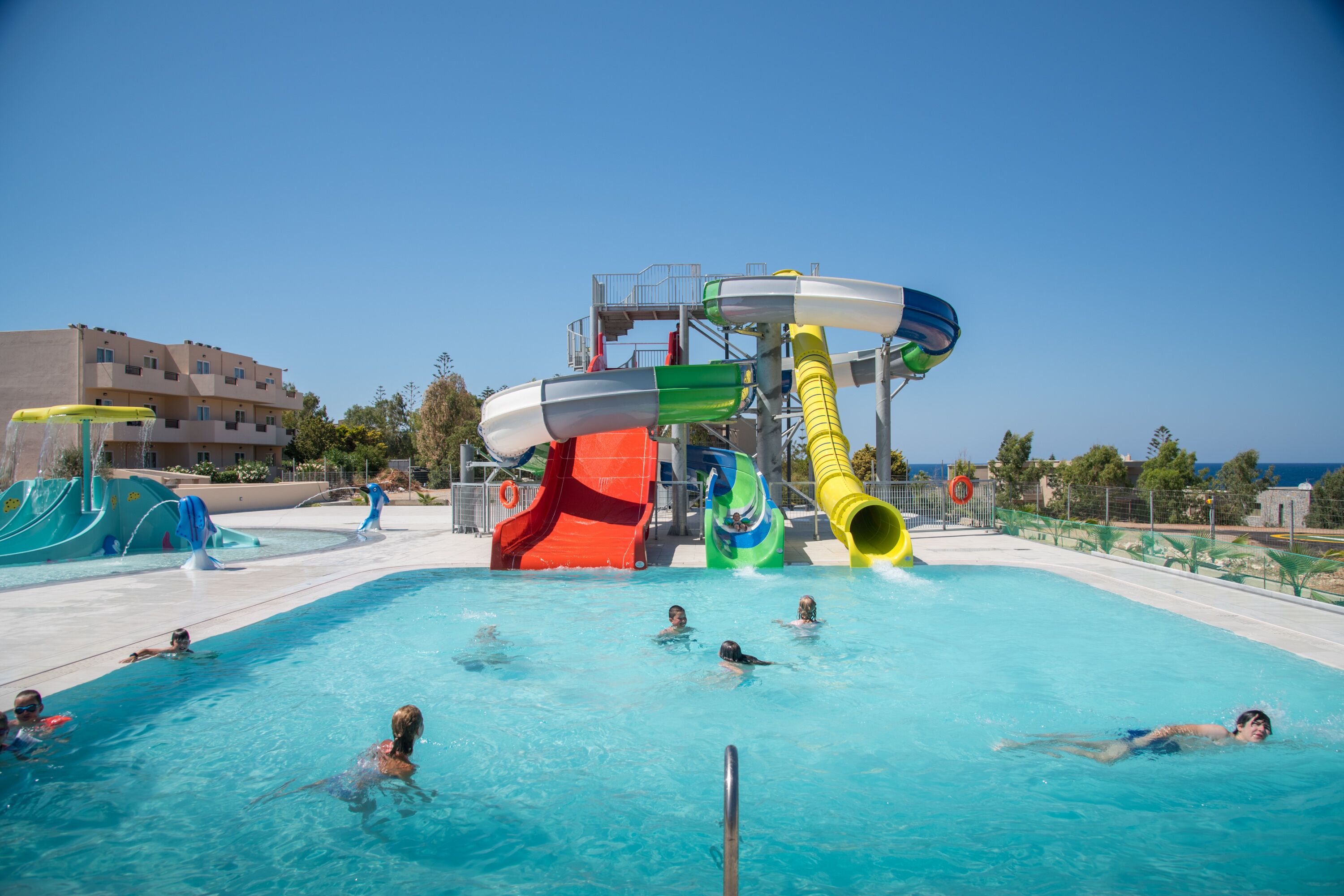 Una piscina con toboganes acuáticos múltiples y una torre de salvavidas.